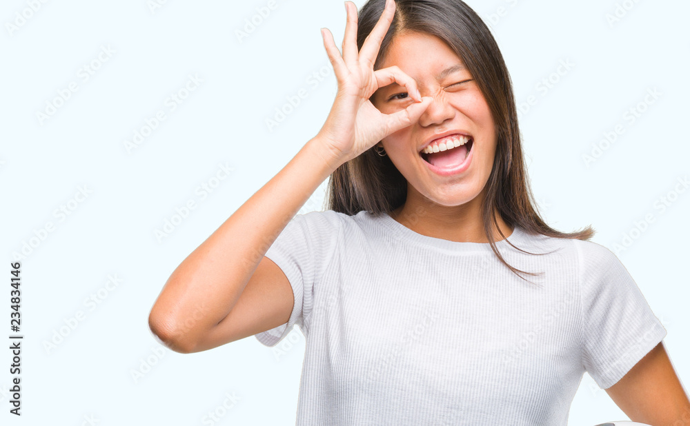 Young asian woman holding football soccer ball over isolated background with happy face smiling doing ok sign with hand on eye looking through fingers Young asian woman holding football soccer ball over isolated background with happy face smiling doing ok sign with hand on eye looking through fingers