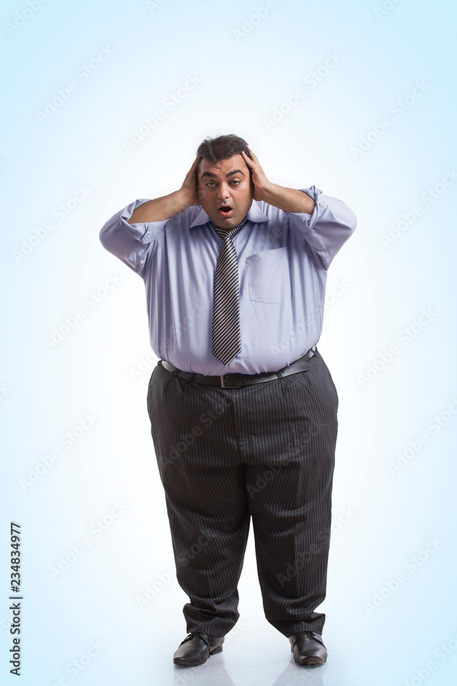 Overweight man in formal clothes holding his head with both hands with an expression of shock Overweight man in formal clothes holding his head with both hands with an expression of shock