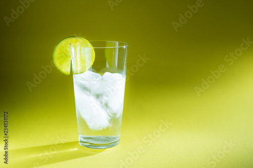 pure water in a glass of real ice and a slice of fresh lime in the rays of light