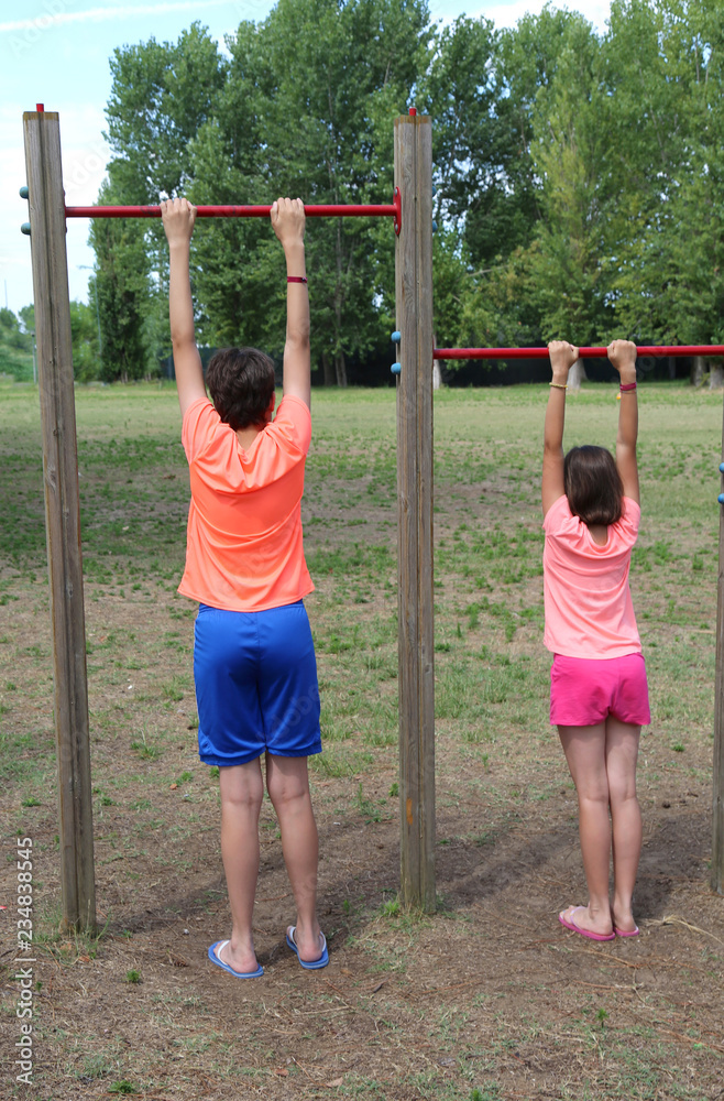 two children do gym exercises at the outdoor bar two children do gym exercises at the outdoor bar