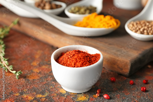 Bowl with chili pepper powder on color table