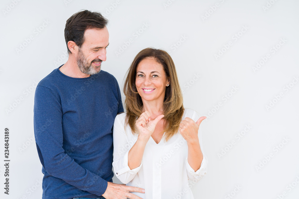 Beautiful middle age couple in love over isolated background Pointing to the back behind with hand and thumbs up, smiling confident Beautiful middle age couple in love over isolated background Pointing to the back behind with hand and thumbs up, smiling confident