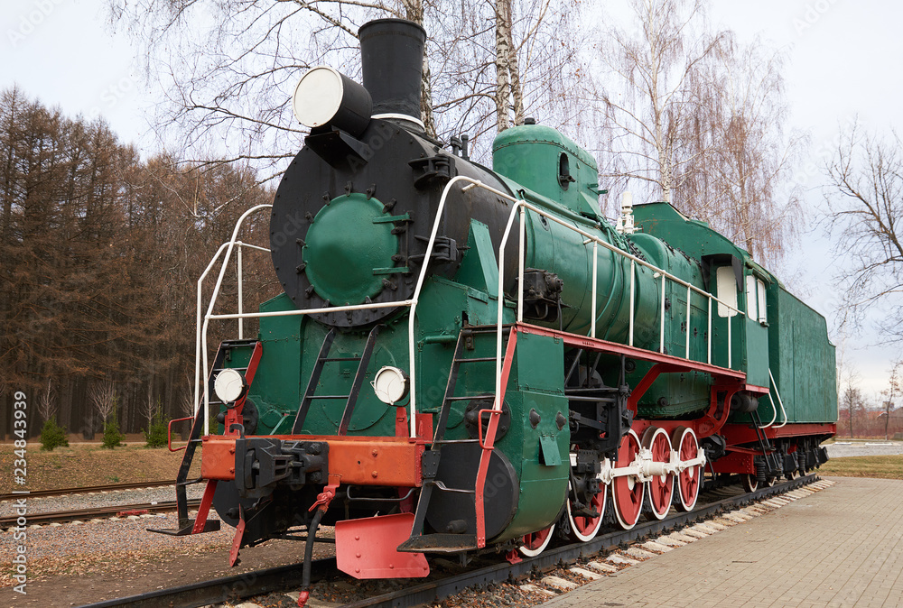 Fototapeta premium Front side view of classic old green steam locomotive on rail tracks