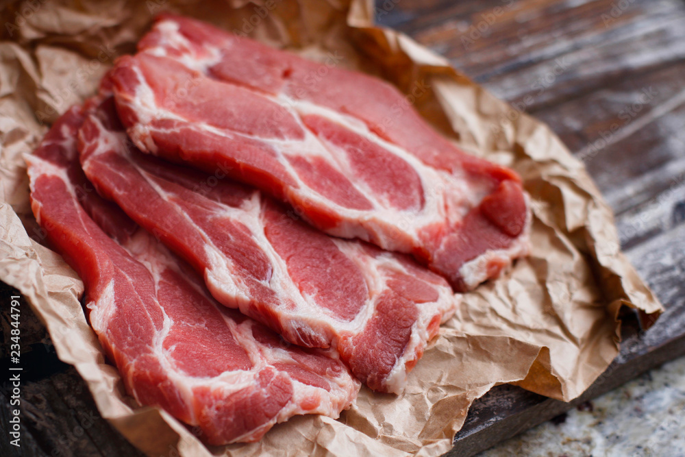 Fresh red chop meat on cooking paper. Dark red raw sliced meat on wooden table. Fresh red chop meat on cooking paper. Dark red raw sliced meat on wooden table.