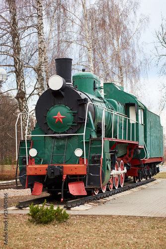 Front side view of classic old green soviet steam locomotive with red star on rail tracks