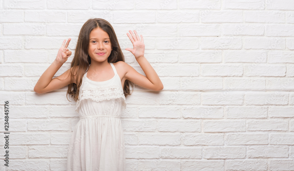 Young hispanic kid over white brick wall showing and pointing up with fingers number seven while smiling confident and happy. Young hispanic kid over white brick wall showing and pointing up with fingers number seven while smiling confident and happy.