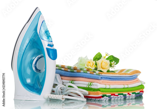 Electric iron and folded clean laundry isolated on white