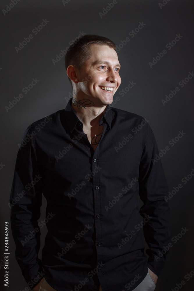Portrait of determined goodlooking man wearing black shirt, black background.