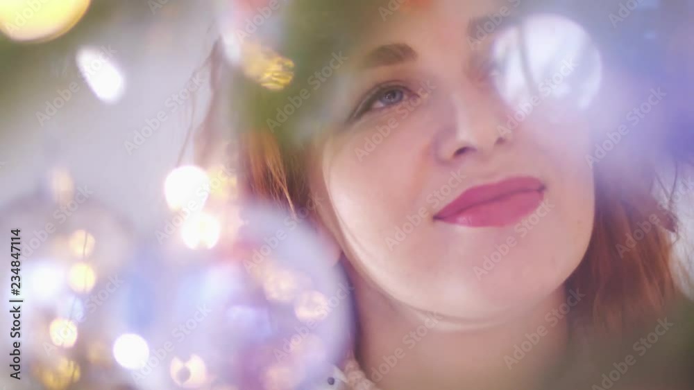 Young beautiful mysterious smiling woman looking through the lights of the garland. slow motion. 3840x2160 Young beautiful mysterious smiling woman looking through the lights of the garland. slow motion. 3840x2160