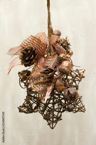 Christmas toy in the shape of a star of twigs, cones and acorns decorated with gold bows
