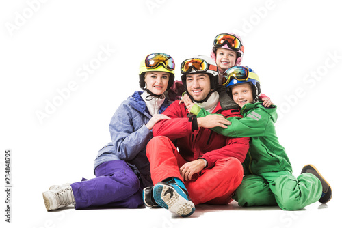 Happy family sitting in snowsuits and smiling isolated on white