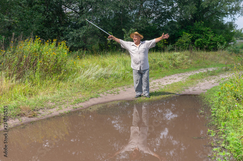 Senior man shows how big is a puddle on the country road