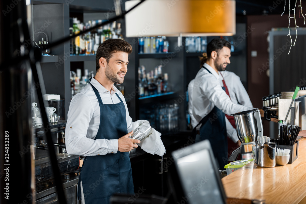 handsome smiling barman rubbing up glass with cloth at workplace handsome smiling barman rubbing up glass with cloth at workplace