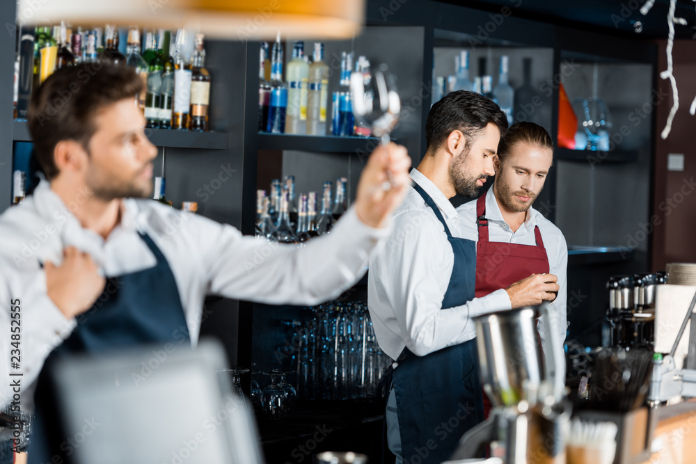 barmen team in aprons standing at workplace near counter barmen team in aprons standing at workplace near counter