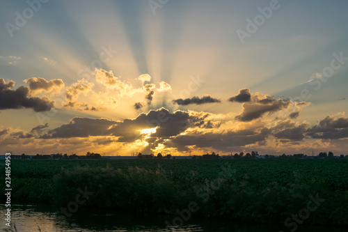 Crepuscular rays (or sunbeams) from behind the clouds, over the dutch countryside © Menyhert
