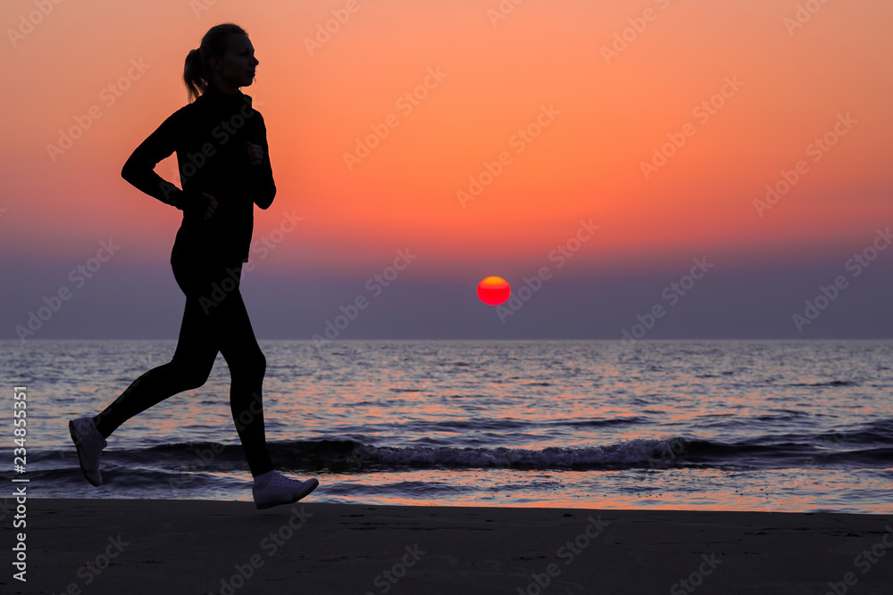 Alone woman running on sand beach. Beautiful red sunset. Enjoying sport in evening. Copy space. Empty place for motivational, inspirational text, quote or sayings on sky background. Side view.