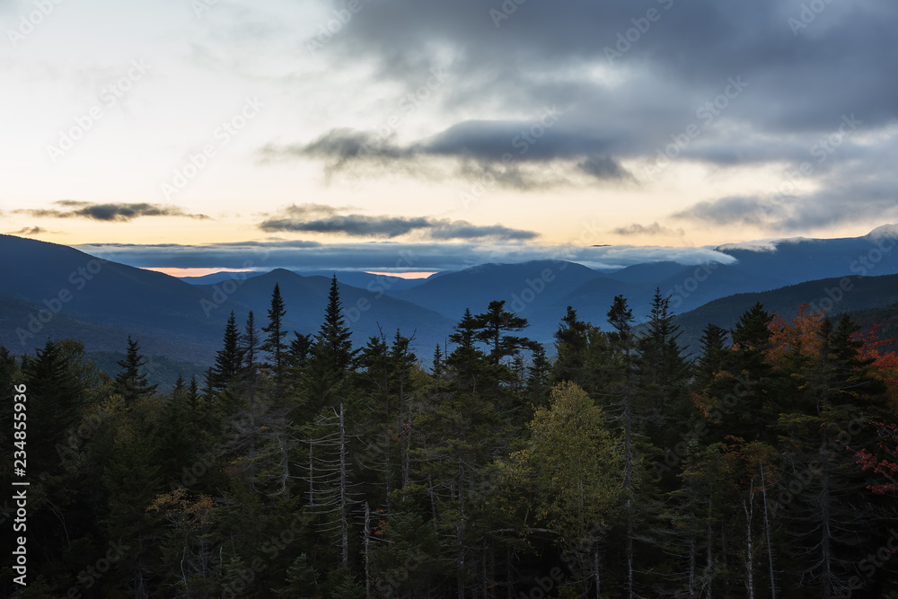 Wooded mountains and pink clouds on the peaks at sunset. White Mountain National Park. USA. New Hamshire.
