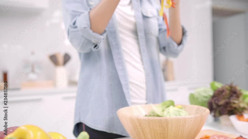 Slow motion - Young Asian woman making salad healthy food in the kitchen, beautiful female in casual use organic vegetables lots of nutrition preparing salad for fit body at home. Healthy food concept Slow motion - Young Asian woman making salad healthy food in the kitchen, beautiful female in casual use organic vegetables lots of nutrition preparing salad for fit body at home. Healthy food concept