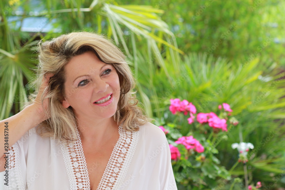 Attractive middle age woman in front of beautiful green palm leaves Attractive middle age woman in front of beautiful green palm leaves