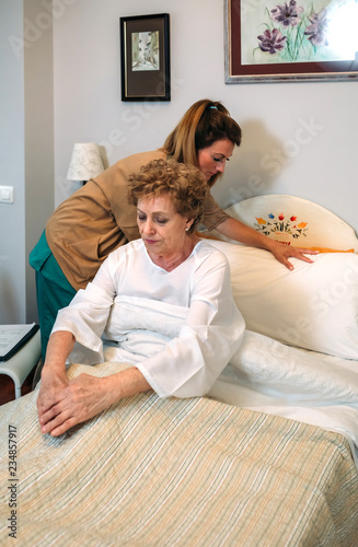 Female caregiver accommodating the pillow to elderly female patient
