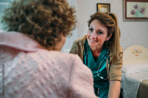 Foto Female doctor talking to elderly female patient in a wheelchair