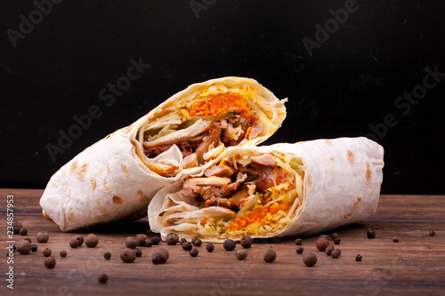 Shawarma sandwich gyro fresh roll of lavash (pita bread) chicken beef shawarma falafel RecipeTin Eatsfilled with grilled meat, mushrooms, cheese. Traditional Middle Eastern snack. On black background photo