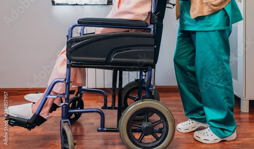 Female doctor carrying elderly female patient in a wheelchair
