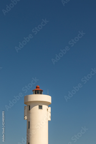 The top of a lighthouse isolated against a clear blue sky image with copy space in portrait format