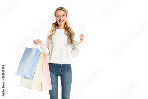 smiling blonde woman holding shopping bags and tablet isolated on white