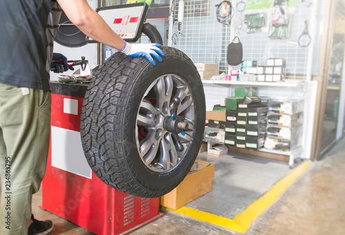 Mechanic balancing a car wheel on an automated machine at the garage.