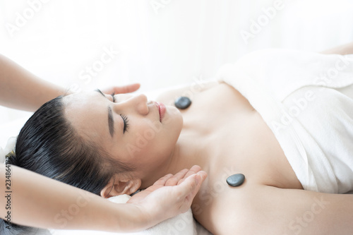 beautiful and healthy young woman relaxing with back stone therapy massage in spa salon