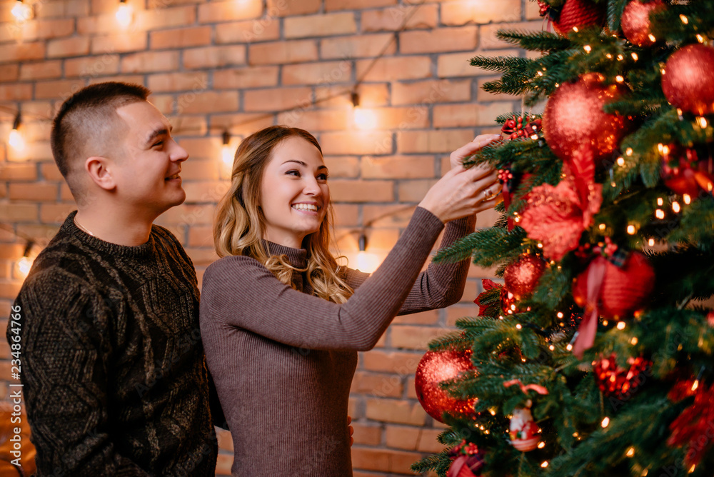 young couple decorating christmas tree together at home