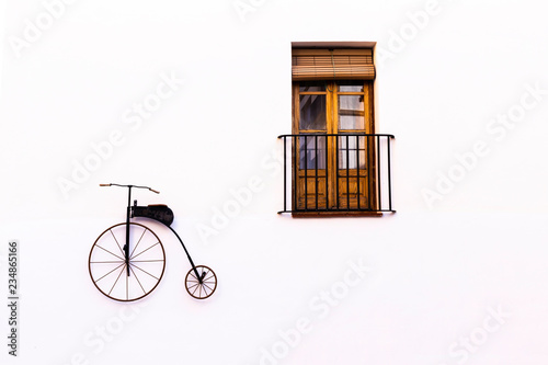 Old-fashioned bike and window with balcony as decor on a white wall. Copy space.