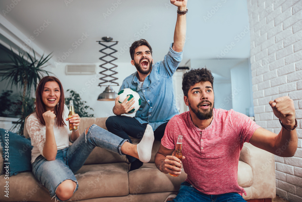 Happy friends or football fans watching soccer on tv and celebrating victory at home.Friendship, sports and entertainment concept. Happy friends or football fans watching soccer on tv and celebrating victory at home.Friendship, sports and entertainment concept.