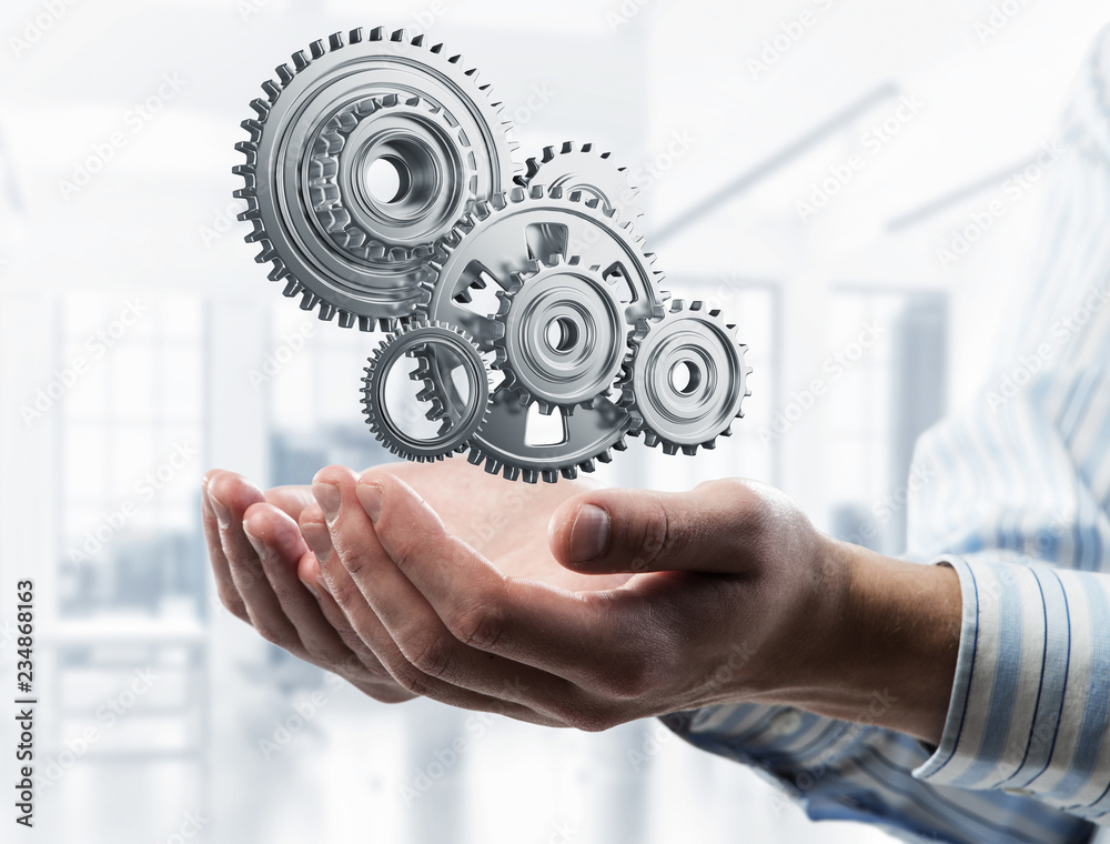 Engine mechanism in male ahnds as symbol for cooperation or team Engine mechanism in male ahnds as symbol for cooperation or team