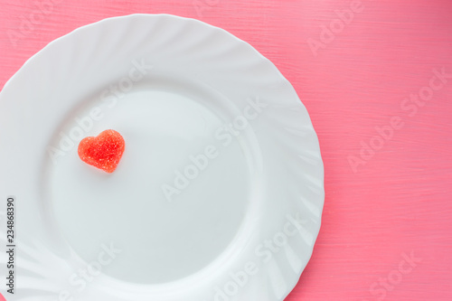 Heart shaped marmalade on a white plate against a pink background. Concept valentine day