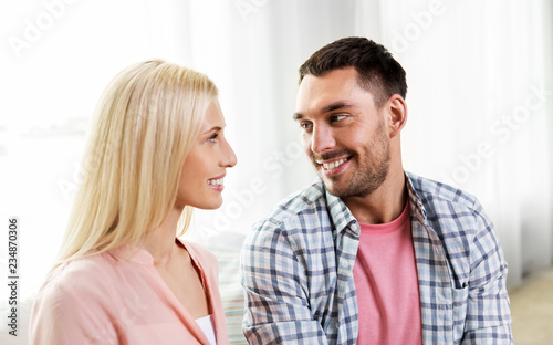 love, relationships and people concept - smiling happy couple looking at each other at home