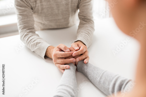old age  family  care and support concept - close up of young woman holding senior man hands
