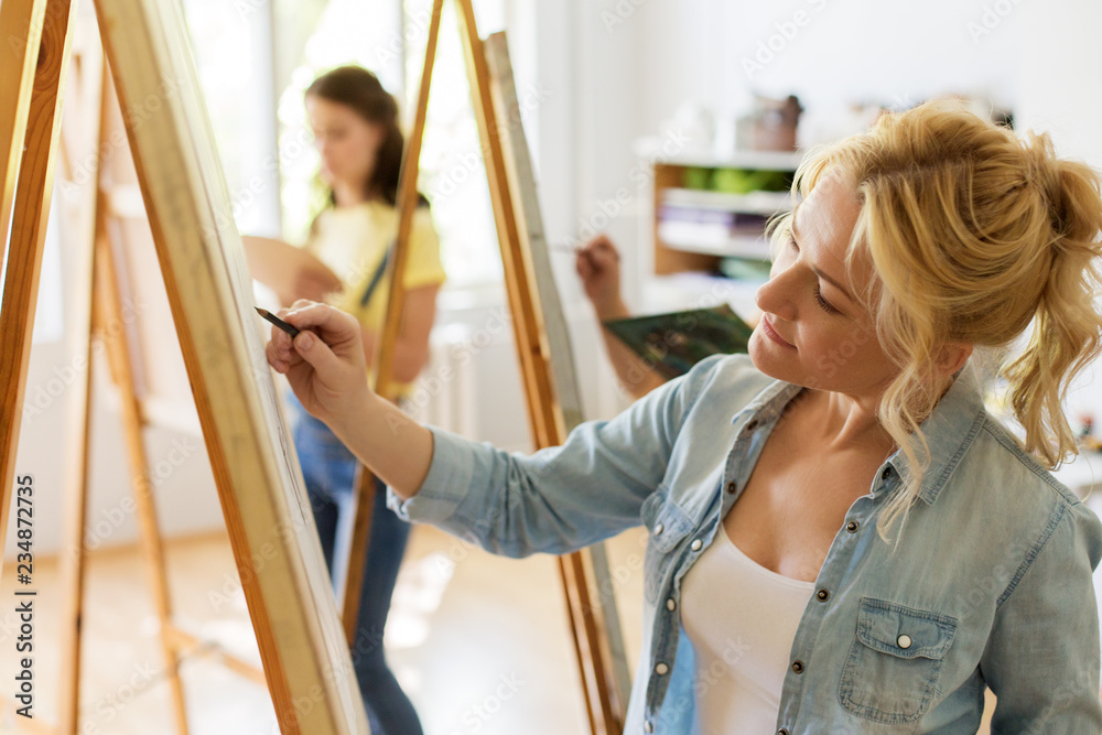 art school, creativity and people concept - woman with easel drawing at studio art school, creativity and people concept - woman with easel drawing at studio