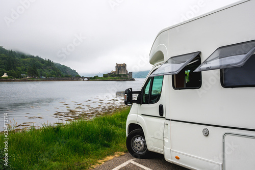 Camper car in front of Eilean Donan castle among scottish mist