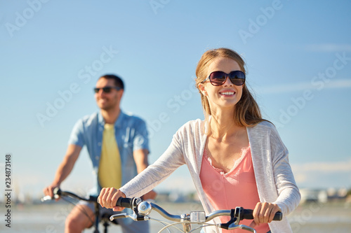 people, leisure and lifestyle concept - happy young couple riding bicycles on beach © Syda Productions