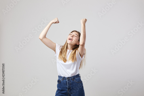 Cheerful and calm girl dressed in a white t-shirt and jeans has fun on a white background in the studio