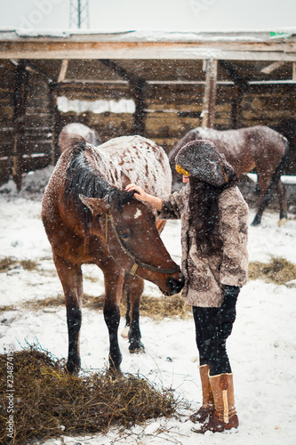 young womanl stroking young cute foal in the snow