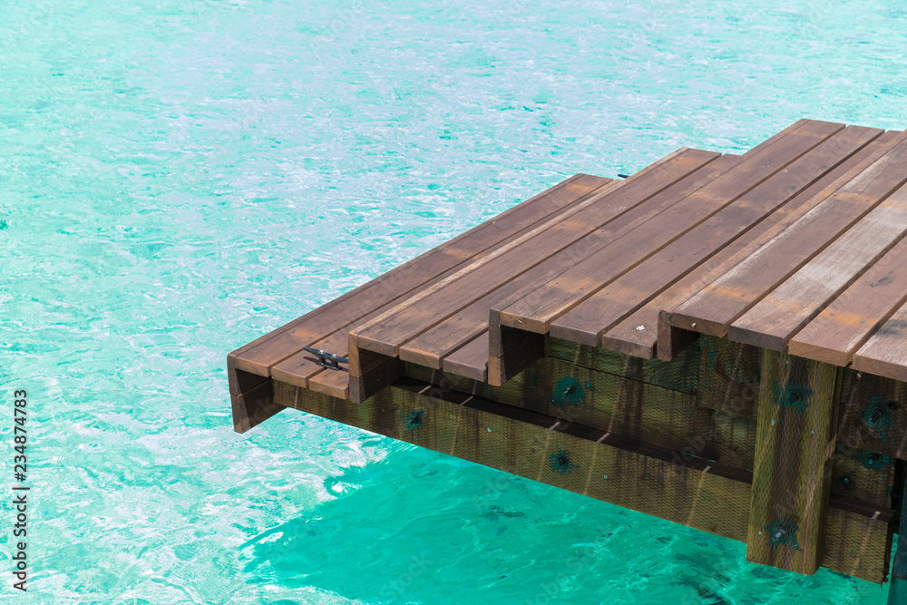 travel, tourism, vacation and summer holidays concept - wooden pier with stair in sea water in french polynesia