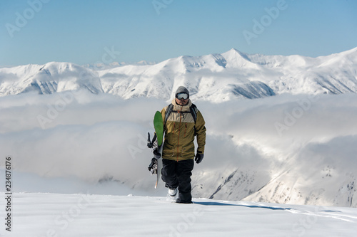 Manful snowboarder walking in the mountain resort