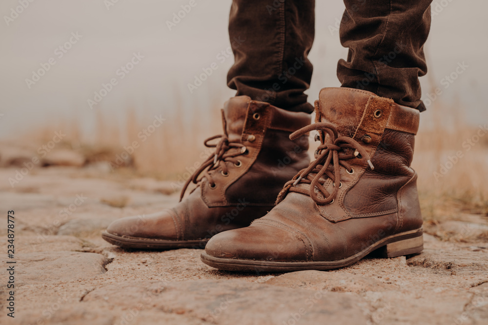 Image of mans legs in old boots. Concept of selling shoes. Autumn time.  Horizontal view. Outdoor shot. Footwear Stock Photo | Adobe Stock