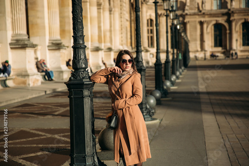 Young girl in sunglasses and brown coat walk in the cetnre of city