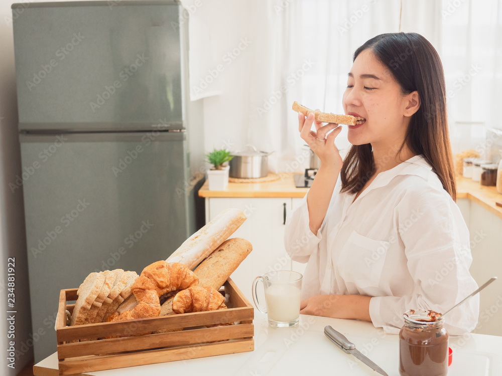 young asian woman making sandwiches and eat bread in kitchen