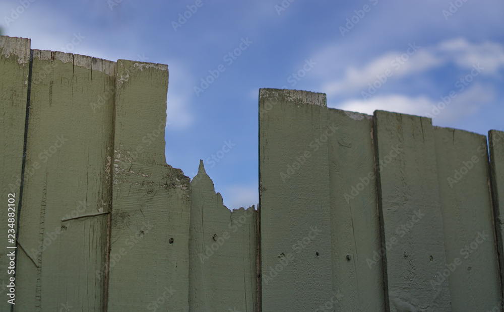 Broken wooden fence with blue sky background