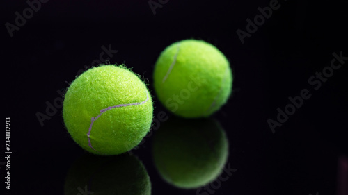 Yellow tennis ball in network package on black background © Olya
